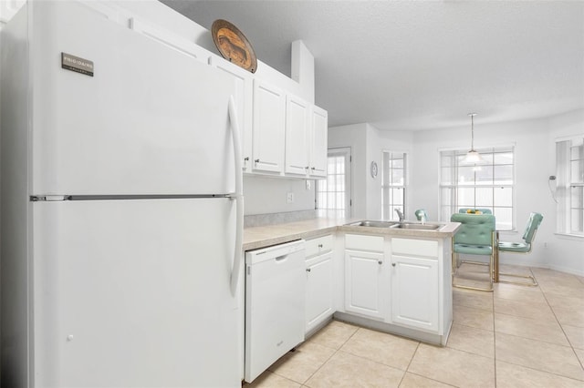 kitchen featuring white appliances, light countertops, a peninsula, and white cabinets