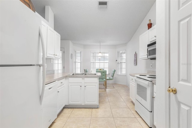 kitchen featuring visible vents, light countertops, white cabinetry, white appliances, and a peninsula