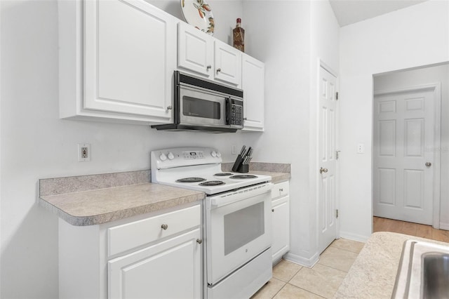 kitchen featuring white electric range oven, light countertops, stainless steel microwave, white cabinetry, and light tile patterned flooring