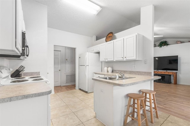 kitchen with white cabinets, a breakfast bar area, light countertops, a sink, and range with electric stovetop