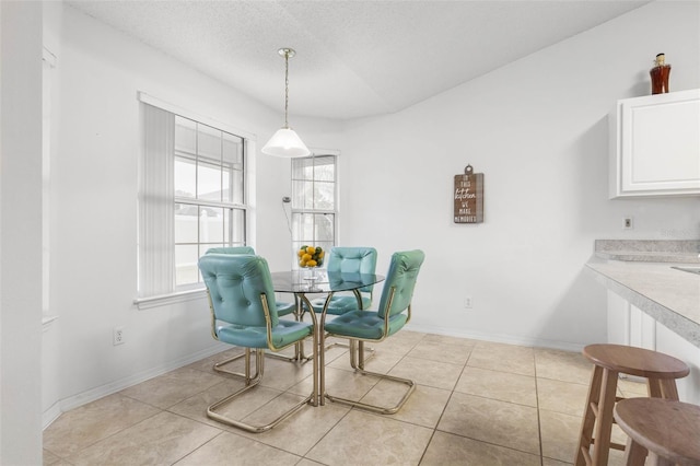 dining area with a textured ceiling, light tile patterned flooring, and baseboards