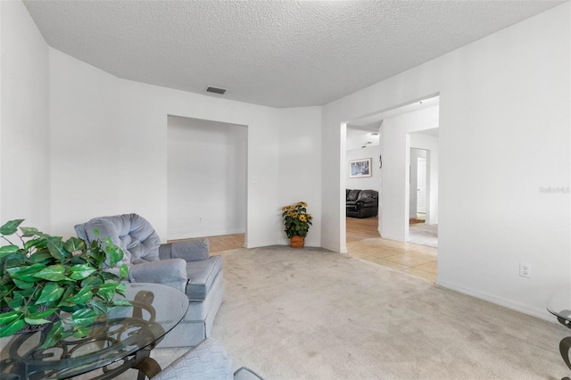 unfurnished room featuring light carpet, visible vents, and a textured ceiling