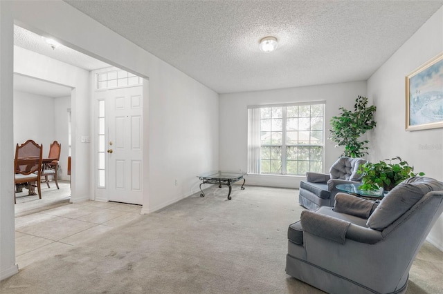 living area featuring light carpet, a textured ceiling, and baseboards