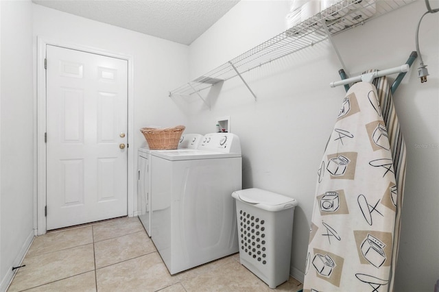 laundry area featuring light tile patterned floors, laundry area, a textured ceiling, and washing machine and dryer