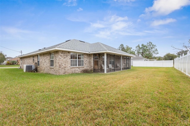 back of property featuring central air condition unit, a sunroom, a fenced backyard, and a lawn