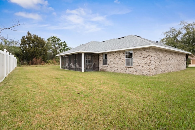 rear view of property with a sunroom, fence, and a lawn