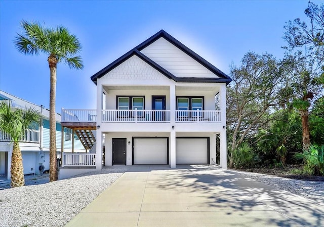 raised beach house with a garage, concrete driveway, stairway, and covered porch