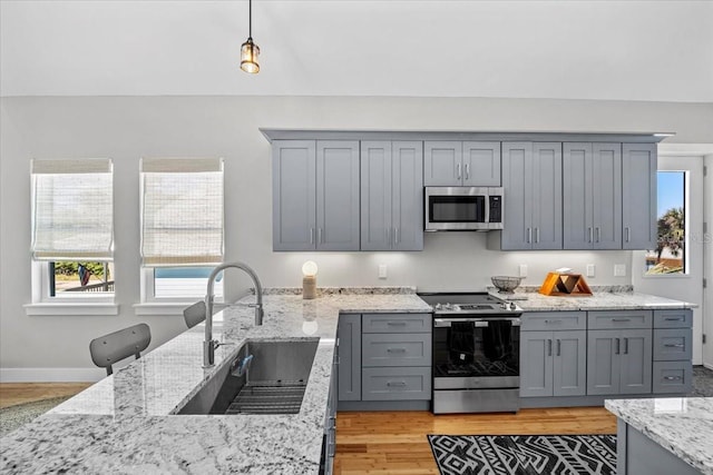 2737 John Bull, Flagler Beach, FL 32136 - kitchen featuring light stone counters, light wood-style flooring, gray cabinetry, stainless steel appliances, and a sink