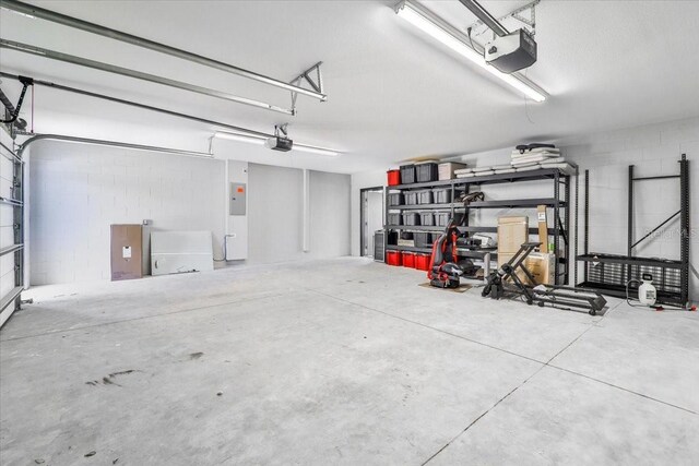 2737 John Bull, Flagler Beach, FL 32136 - garage featuring electric panel, concrete block wall, and a garage door opener