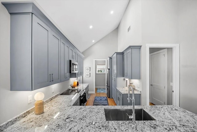 2737 John Bull, Flagler Beach, FL 32136 - kitchen with light wood-style flooring, gray cabinetry, a sink, light stone countertops, and stainless steel microwave