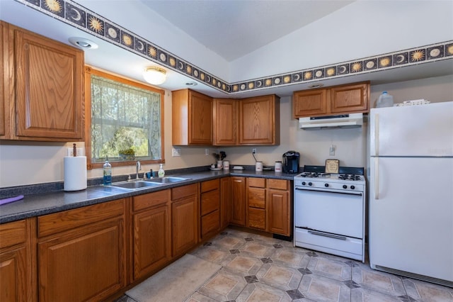 kitchen with dark countertops, white appliances, under cabinet range hood, and a sink