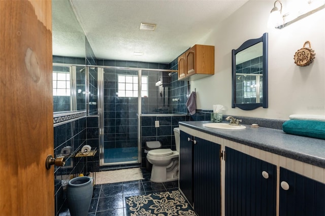 bathroom featuring visible vents, toilet, a textured ceiling, vanity, and a shower stall