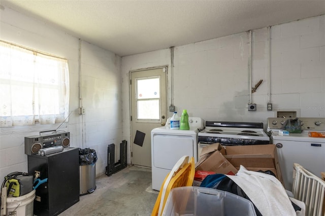 miscellaneous room with concrete block wall, concrete floors, a textured ceiling, and separate washer and dryer