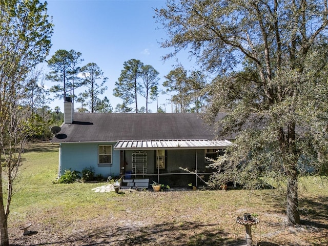 back of property featuring a sunroom, a chimney, and a yard