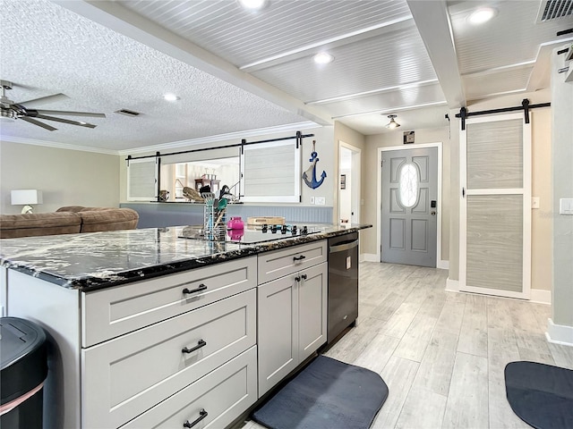 kitchen featuring black appliances, a barn door, and dark stone counters