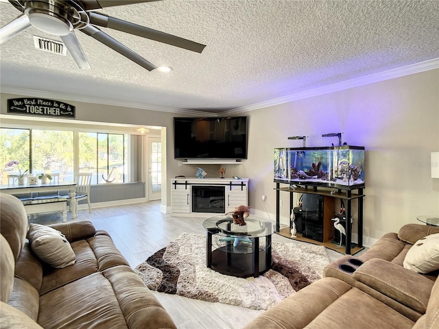 living room featuring light wood-style flooring, ornamental molding, and a glass covered fireplace