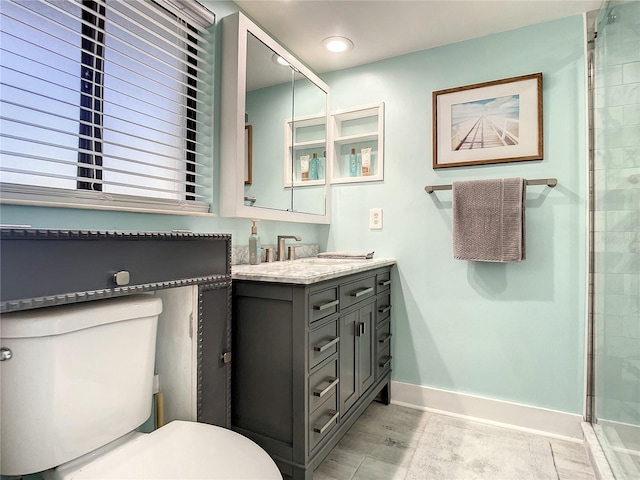 full bath featuring toilet, a stall shower, vanity, baseboards, and tile patterned floors