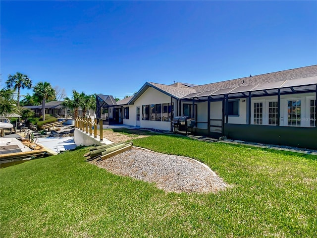 rear view of property with a lanai, a lawn, and stucco siding