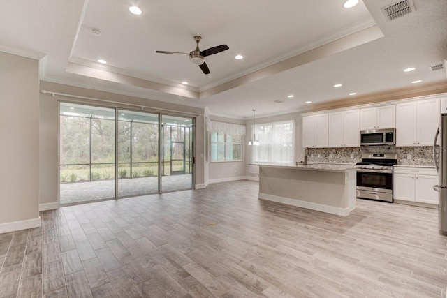 1068 Sea Shell Ct, Daytona Beach, FL 32124 - kitchen with a tray ceiling, stainless steel appliances, decorative backsplash, light wood-style floors, and open floor plan