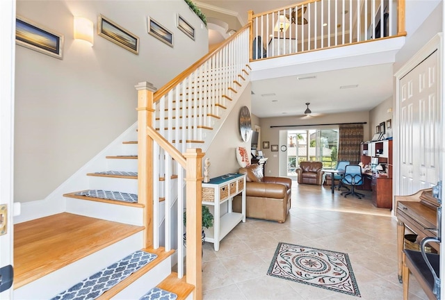 stairs with ceiling fan, a towering ceiling, and tile patterned floors