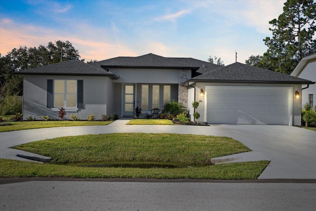 view of front facade with roof with shingles, stucco siding, concrete driveway, a lawn, and an attached garage