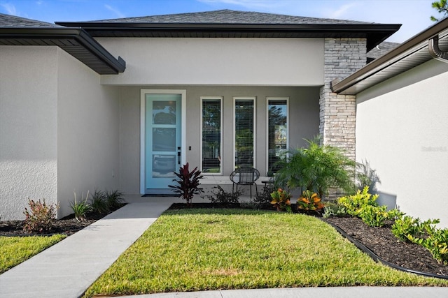 entrance to property featuring a porch, stone siding, a lawn, and stucco siding