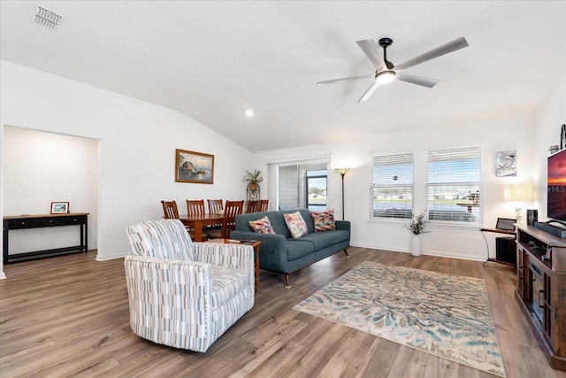 living area with vaulted ceiling, wood finished floors, visible vents, and baseboards