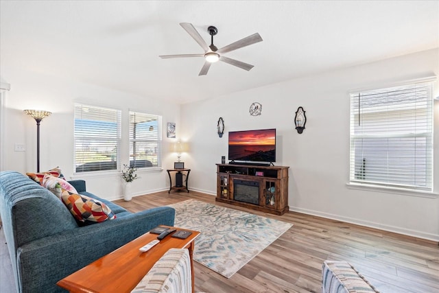 living area featuring ceiling fan, light wood-type flooring, and baseboards