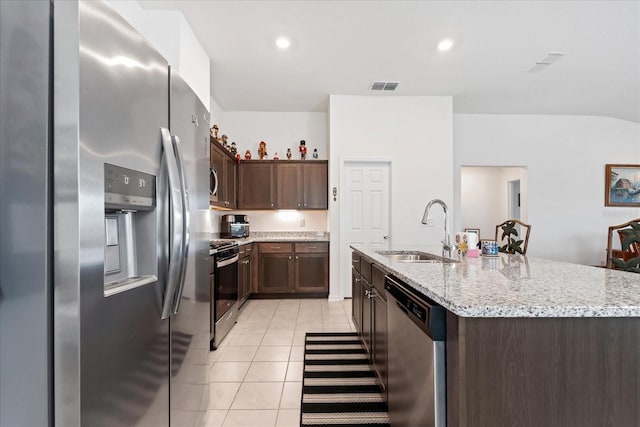 kitchen with a kitchen island with sink, a sink, visible vents, appliances with stainless steel finishes, and light stone countertops