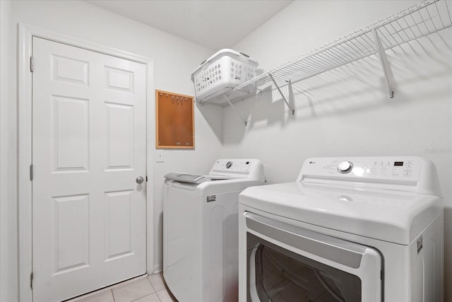 laundry room featuring light tile patterned floors, laundry area, and washing machine and dryer