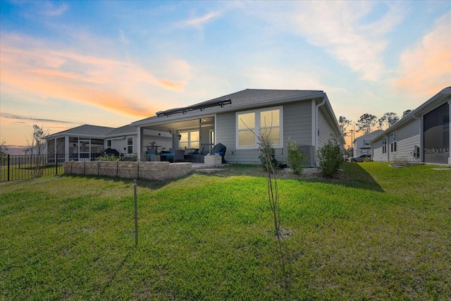 back of property at dusk featuring a yard, a patio area, fence, and an outdoor living space