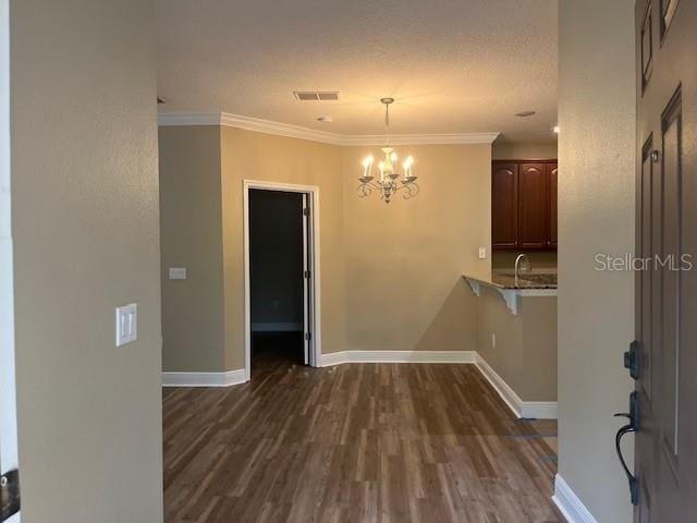 unfurnished dining area with crown molding, visible vents, dark wood-type flooring, a sink, and baseboards