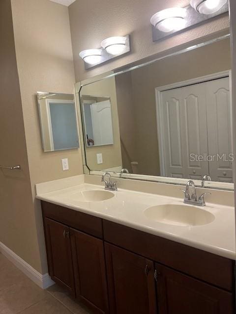 bathroom featuring double vanity, tile patterned flooring, baseboards, and a sink