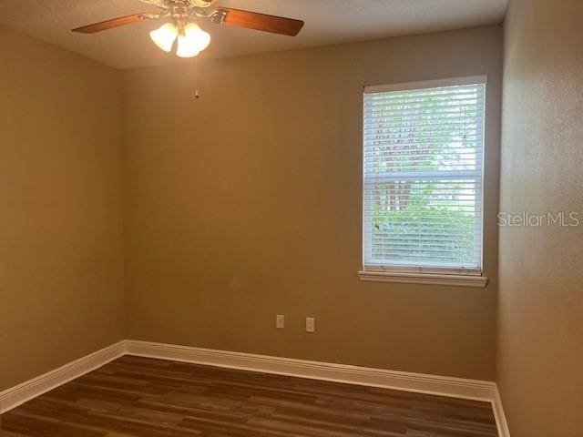 unfurnished room featuring dark wood-style floors, baseboards, and a ceiling fan