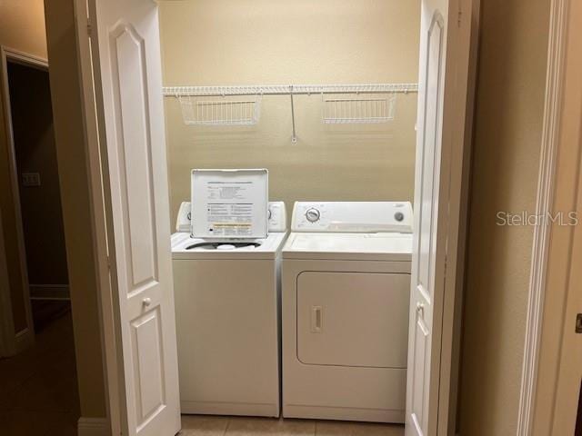 laundry area featuring laundry area, light tile patterned flooring, and washing machine and clothes dryer