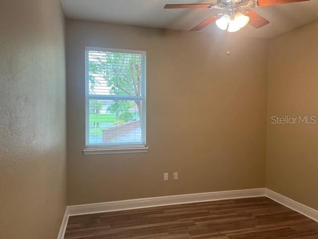 spare room with ceiling fan, dark wood-type flooring, and baseboards