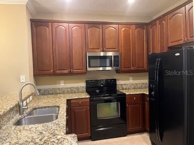 kitchen featuring light stone counters, a sink, black appliances, and light tile patterned floors