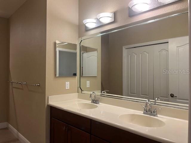 bathroom with a sink, baseboards, and double vanity