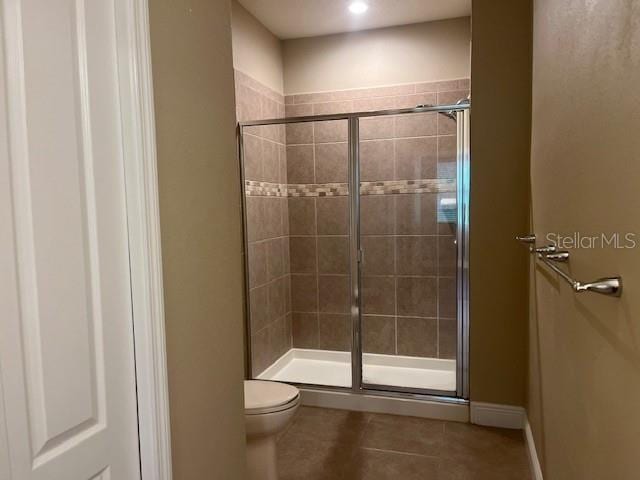 bathroom featuring a shower stall, toilet, and tile patterned floors