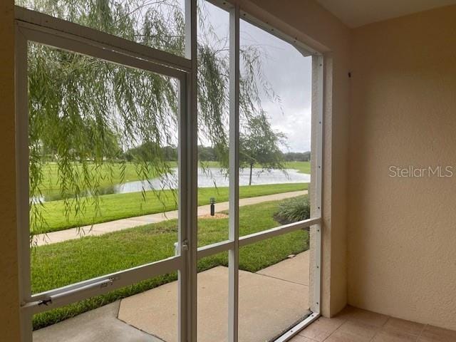 doorway to outside with a textured wall, a water view, and tile patterned floors