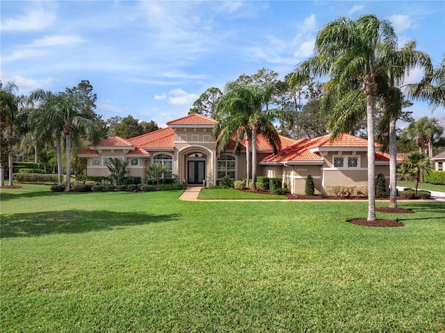 mediterranean / spanish house with french doors, a front lawn, a tile roof, and stucco siding