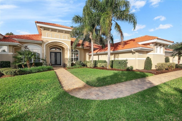 mediterranean / spanish-style house with a tiled roof, a front yard, and stucco siding