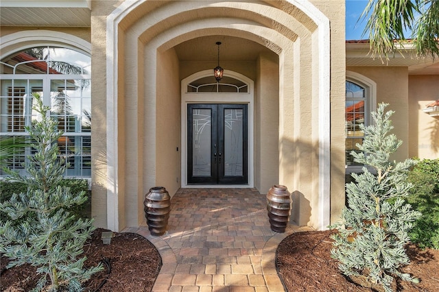 view of exterior entry featuring french doors and stucco siding