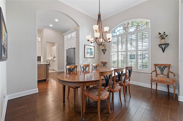 dining space with baseboards, arched walkways, dark wood-type flooring, crown molding, and a notable chandelier