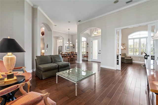 living room featuring baseboards, arched walkways, dark wood-style flooring, and ornamental molding