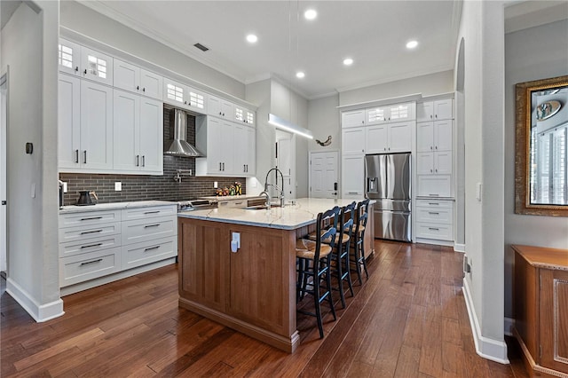 kitchen with glass insert cabinets, white cabinets, and wall chimney range hood