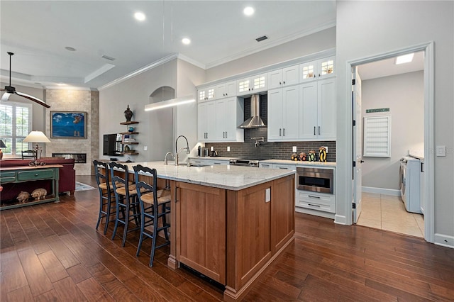 kitchen featuring a large island with sink, a sink, glass insert cabinets, and white cabinets