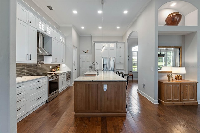 kitchen featuring a center island with sink, white cabinets, light stone counters, stainless steel appliances, and a sink