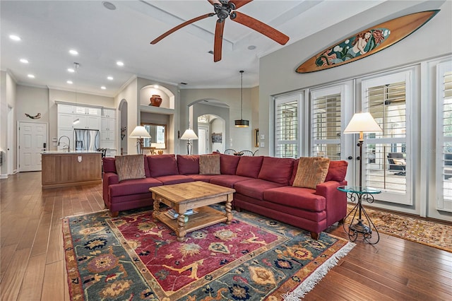 living room with ornamental molding, arched walkways, dark wood finished floors, and recessed lighting