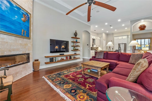 living area featuring recessed lighting, dark wood-type flooring, ornamental molding, a large fireplace, and baseboards